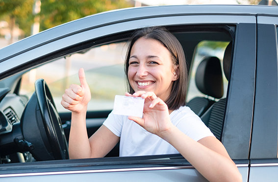 smiling girl in car holding licence